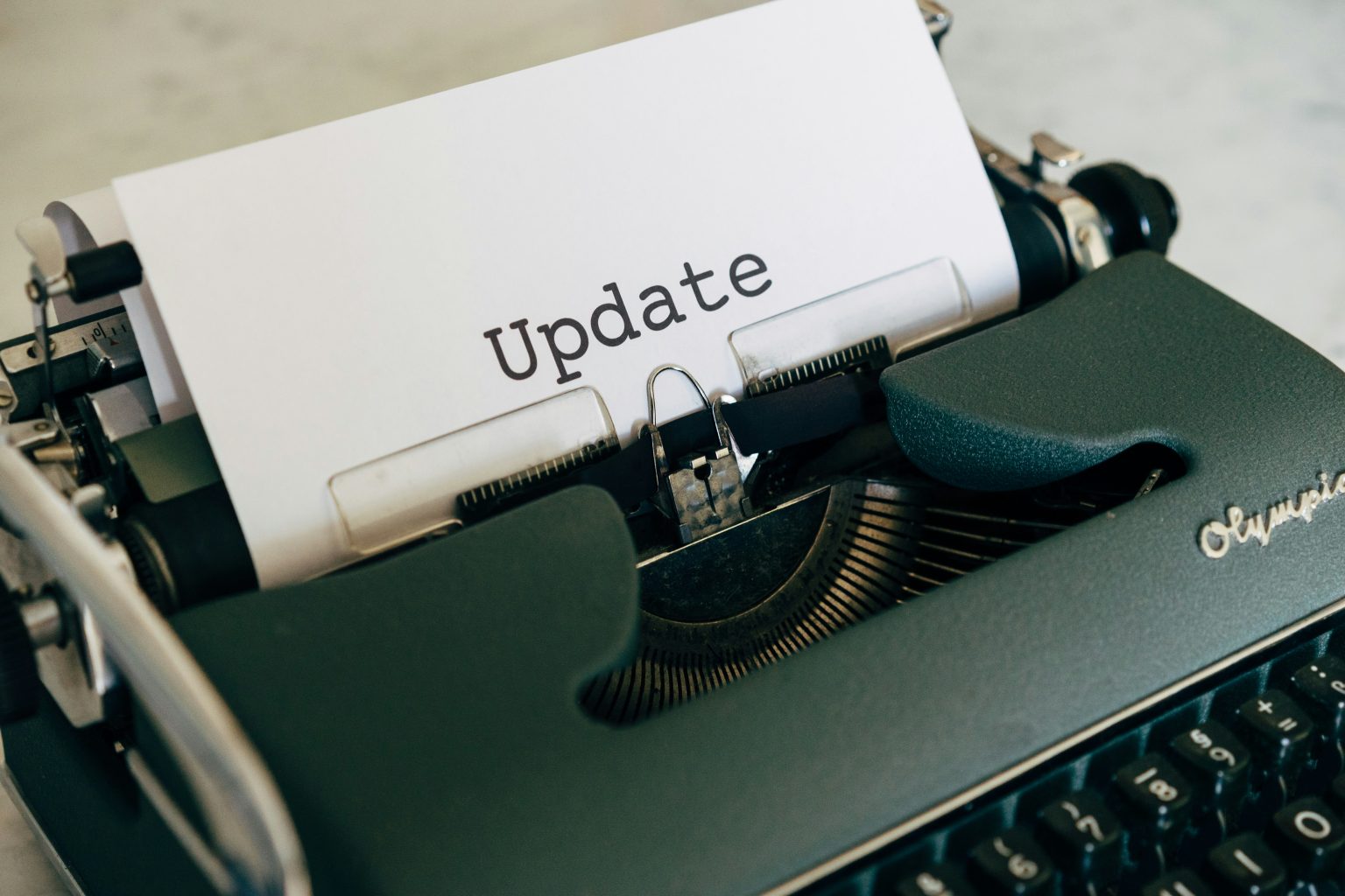White printer paper showing the word Update on a green typewriter