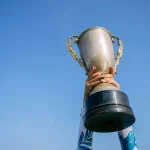 Hands holding a trophy high against a clear blue sky symbolizing victory in community contests